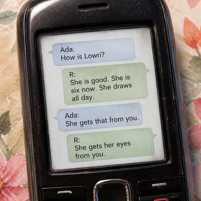 Charming ink and watercolor painting, clean lines, vibrant but soft color palette, storybook style. A close-up photo of an old phone screen showing a text exchange. Visible text: "Ada: How is Lowri? — R: She is good. She is six now. She draws all day. — Ada: She gets that from you. — R: She gets her eyes from you." No other readable text.