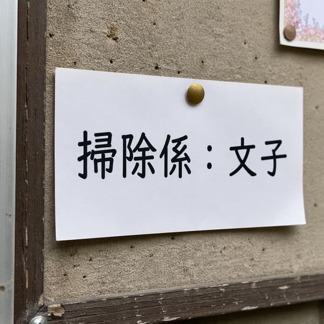 A close-up photo of a neighborhood noticeboard. A piece of paper is pinned to it with the text '掃除係：文子' written in clear, bold Japanese characters
Chat attachment instruction: Generate exactly one in-world chat attachment, not a collage, split-screen, comic panel, flashback, or explanatory scene. If the prompt is a screenshot, phone screen, document, note, card, map, receipt, label, object photo, or photo someone took, frame that artifact directly. A name appearing in visible text or in 'photo taken by X' is not an instruction to draw that person. Do not show recurring story participants as visible people unless the prompt itself explicitly says they are visible. Keep unrequested people, faces, and bodies out of the image. Do not add readable text unless the prompt explicitly asks for visible text.
