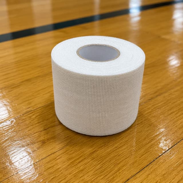 A single white sports tape roll on a polished wooden gym floor, clean and simple
Chat attachment instruction: Generate exactly one in-world chat attachment, not a collage, split-screen, comic panel, flashback, or explanatory scene. If the prompt is a screenshot, phone screen, document, note, card, map, receipt, label, object photo, or photo someone took, frame that artifact directly. A name appearing in visible text or in 'photo taken by X' is not an instruction to draw that person. Do not show recurring story participants as visible people unless the prompt itself explicitly says they are visible. Keep unrequested people, faces, and bodies out of the image. Do not add readable text unless the prompt explicitly asks for visible text.