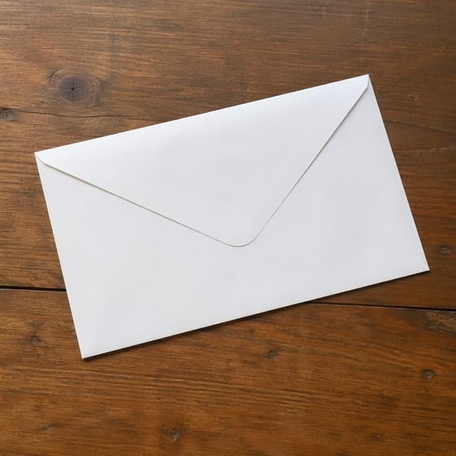 A plain white paper envelope on a wooden surface
Chat attachment instruction: Generate exactly one in-world chat attachment, not a collage, split-screen, comic panel, flashback, or explanatory scene. If the prompt is a screenshot, phone screen, document, note, card, map, receipt, label, object photo, or photo someone took, frame that artifact directly. A name appearing in visible text or in 'photo taken by X' is not an instruction to draw that person. Do not show recurring story participants as visible people unless the prompt itself explicitly says they are visible. Keep unrequested people, faces, and bodies out of the image. Do not add readable text unless the prompt explicitly asks for visible text.