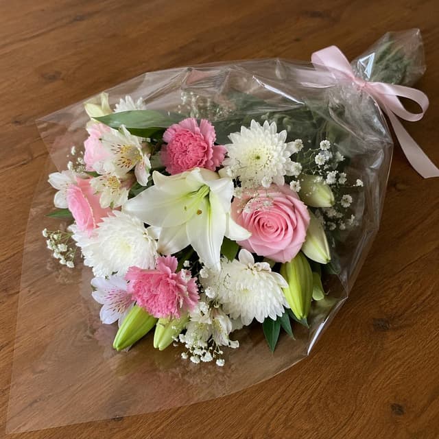 a bouquet of white and pink flowers in clear plastic wrapping, resting on a plain wooden table
Chat attachment instruction: Generate exactly one in-world chat attachment, not a collage, split-screen, comic panel, flashback, or explanatory scene. If the prompt is a screenshot, phone screen, document, note, card, map, receipt, label, object photo, or photo someone took, frame that artifact directly. A name appearing in visible text or in 'photo taken by X' is not an instruction to draw that person. Do not show recurring story participants as visible people unless the prompt itself explicitly says they are visible. Keep unrequested people, faces, and bodies out of the image.