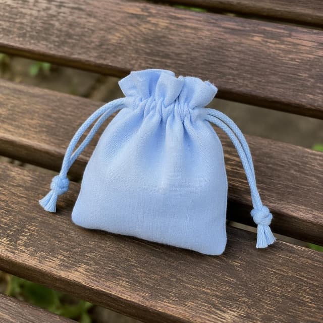 a small pale blue fabric drawstring pouch resting on a wooden bench
Chat attachment instruction: Generate exactly one in-world chat attachment, not a collage, split-screen, comic panel, flashback, or explanatory scene. If the prompt is a screenshot, phone screen, document, note, card, map, receipt, label, object photo, or photo someone took, frame that artifact directly. A name appearing in visible text or in 'photo taken by X' is not an instruction to draw that person. Do not show recurring story participants as visible people unless the prompt itself explicitly says they are visible. Keep unrequested people, faces, and bodies out of the image.