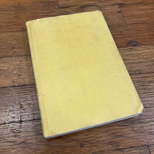 A worn pale-yellow notebook on a wooden floor, plain unlabeled cover
Chat attachment instruction: Generate exactly one in-world chat attachment, not a collage, split-screen, comic panel, flashback, or explanatory scene. If the prompt is a screenshot, phone screen, document, note, card, map, receipt, label, object photo, or photo someone took, frame that artifact directly. A name appearing in visible text or in 'photo taken by X' is not an instruction to draw that person. Do not show recurring story participants as visible people unless the prompt itself explicitly says they are visible. Keep unrequested people, faces, and bodies out of the image.