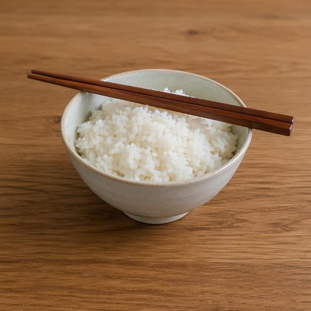 a bowl of white rice with chopsticks resting across the rim on a plain wooden table
Chat attachment instruction: Generate exactly one in-world chat attachment, not a collage, split-screen, comic panel, flashback, or explanatory scene. If the prompt is a screenshot, phone screen, document, note, card, map, receipt, label, object photo, or photo someone took, frame that artifact directly. A name appearing in visible text or in 'photo taken by X' is not an instruction to draw that person. Do not show recurring story participants as visible people unless the prompt itself explicitly says they are visible. Keep unrequested people, faces, and bodies out of the image.