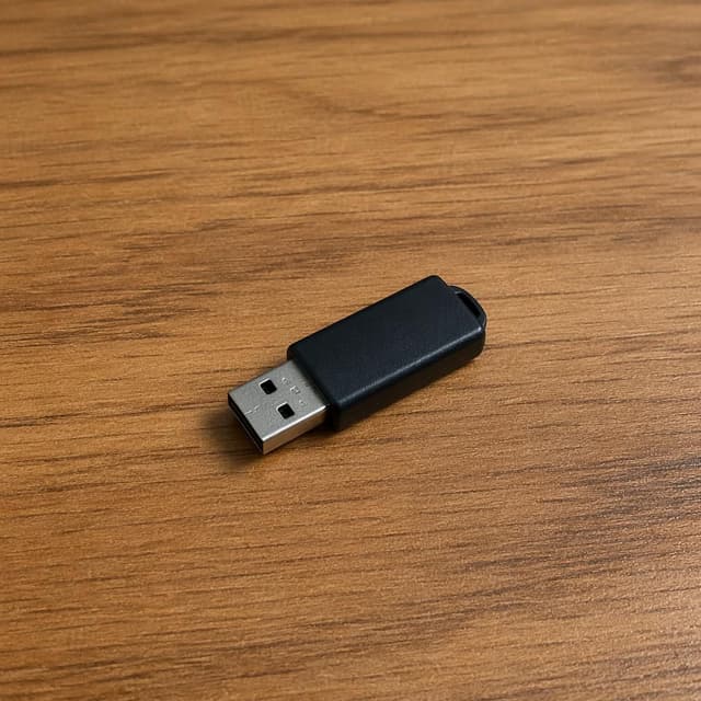 a small black USB drive on a bare wooden desk surface
Chat attachment instruction: Generate exactly one in-world chat attachment, not a collage, split-screen, comic panel, flashback, or explanatory scene. If the prompt is a screenshot, phone screen, document, note, card, map, receipt, label, object photo, or photo someone took, frame that artifact directly. A name appearing in visible text or in 'photo taken by X' is not an instruction to draw that person. Do not show recurring story participants as visible people unless the prompt itself explicitly says they are visible. Keep unrequested people, faces, and bodies out of the image.