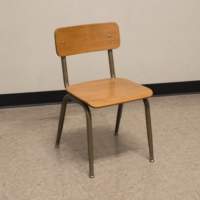 A single plain wooden school chair standing alone on a bare floor
Chat attachment instruction: Generate exactly one in-world chat attachment, not a collage, split-screen, comic panel, flashback, or explanatory scene. If the prompt is a screenshot, phone screen, document, note, card, map, receipt, label, object photo, or photo someone took, frame that artifact directly. A name appearing in visible text or in 'photo taken by X' is not an instruction to draw that person. Do not show recurring story participants as visible people unless the prompt itself explicitly says they are visible. Keep unrequested people, faces, and bodies out of the image.