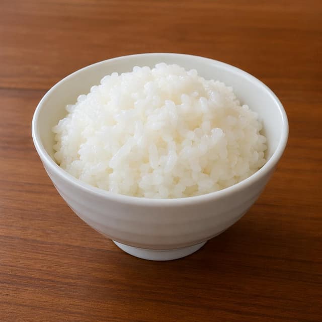 a white ceramic bowl of steamed white rice on a smooth wooden table surface
Chat attachment instruction: Generate exactly one in-world chat attachment, not a collage, split-screen, comic panel, flashback, or explanatory scene. If the prompt is a screenshot, phone screen, document, note, card, map, receipt, label, object photo, or photo someone took, frame that artifact directly. A name appearing in visible text or in 'photo taken by X' is not an instruction to draw that person. Do not show recurring story participants as visible people unless the prompt itself explicitly says they are visible. Keep unrequested people, faces, and bodies out of the image.