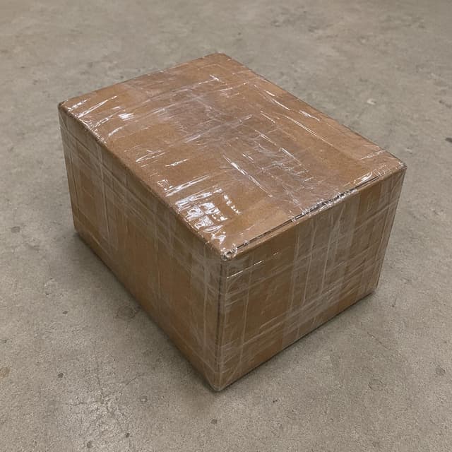 A simple brown cardboard box wrapped tightly with multiple layers of clear packing tape on a plain floor
Chat attachment instruction: Generate exactly one in-world chat attachment, not a collage, split-screen, comic panel, flashback, or explanatory scene. If the prompt is a screenshot, phone screen, document, note, card, map, receipt, label, object photo, or photo someone took, frame that artifact directly. A name appearing in visible text or in 'photo taken by X' is not an instruction to draw that person. Do not show recurring story participants as visible people unless the prompt itself explicitly says they are visible. Keep unrequested people, faces, and bodies out of the image.