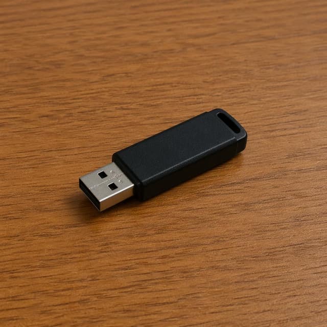 a small black USB flash drive resting on a plain wooden desk surface
Chat attachment instruction: Generate exactly one in-world chat attachment, not a collage, split-screen, comic panel, flashback, or explanatory scene. If the prompt is a screenshot, phone screen, document, note, card, map, receipt, label, object photo, or photo someone took, frame that artifact directly. A name appearing in visible text or in 'photo taken by X' is not an instruction to draw that person. Do not show recurring story participants as visible people unless the prompt itself explicitly says they are visible. Keep unrequested people, faces, and bodies out of the image.