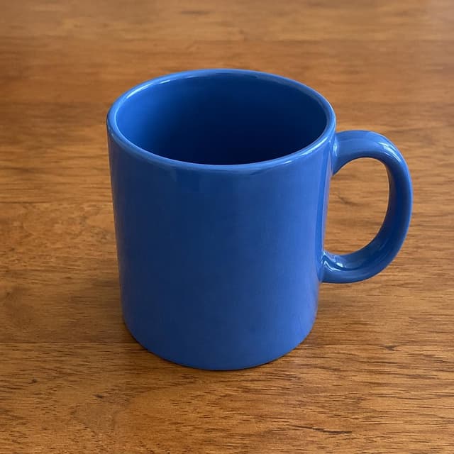 A simple blue ceramic mug sitting on a plain wooden desk surface
Chat attachment instruction: Generate exactly one in-world chat attachment, not a collage, split-screen, comic panel, flashback, or explanatory scene. If the prompt is a screenshot, phone screen, document, note, card, map, receipt, label, object photo, or photo someone took, frame that artifact directly. A name appearing in visible text or in 'photo taken by X' is not an instruction to draw that person. Do not show recurring story participants as visible people unless the prompt itself explicitly says they are visible. Keep unrequested people, faces, and bodies out of the image.