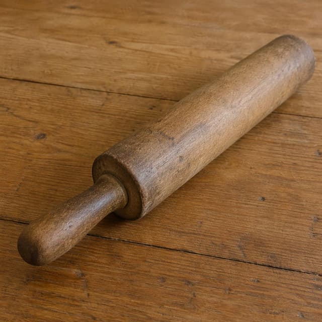 An old wooden rolling pin with a smooth worn handle, lying on a plain wooden table
Chat attachment instruction: Generate exactly one in-world chat attachment, not a collage, split-screen, comic panel, flashback, or explanatory scene. If the prompt is a screenshot, phone screen, document, note, card, map, receipt, label, object photo, or photo someone took, frame that artifact directly. A name appearing in visible text or in 'photo taken by X' is not an instruction to draw that person. Do not show recurring story participants as visible people unless the prompt itself explicitly says they are visible. Keep unrequested people, faces, and bodies out of the image.