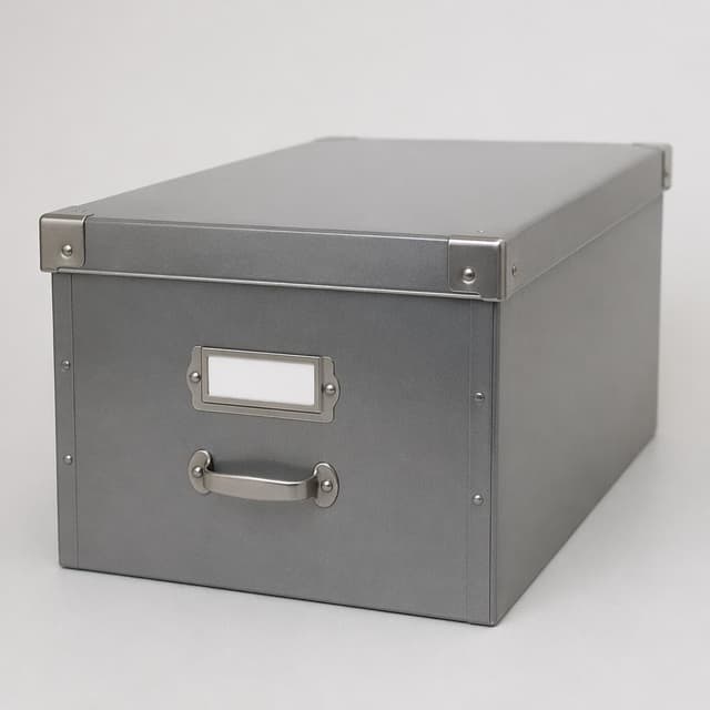 a grey metal archive filing box on a plain surface
Chat attachment instruction: Generate exactly one in-world chat attachment, not a collage, split-screen, comic panel, flashback, or explanatory scene. If the prompt is a screenshot, phone screen, document, note, card, map, receipt, label, object photo, or photo someone took, frame that artifact directly. A name appearing in visible text or in 'photo taken by X' is not an instruction to draw that person. Do not show recurring story participants as visible people unless the prompt itself explicitly says they are visible. Keep unrequested people, faces, and bodies out of the image.