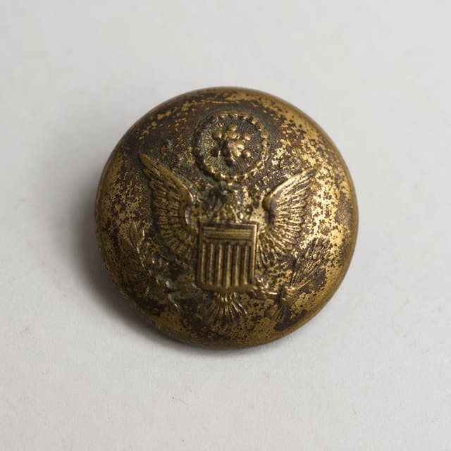 a small tarnished brass military uniform button on a plain surface
Chat attachment instruction: Generate exactly one in-world chat attachment, not a collage, split-screen, comic panel, flashback, or explanatory scene. If the prompt is a screenshot, phone screen, document, note, card, map, receipt, label, object photo, or photo someone took, frame that artifact directly. A name appearing in visible text or in 'photo taken by X' is not an instruction to draw that person. Do not show recurring story participants as visible people unless the prompt itself explicitly says they are visible. Keep unrequested people, faces, and bodies out of the image.