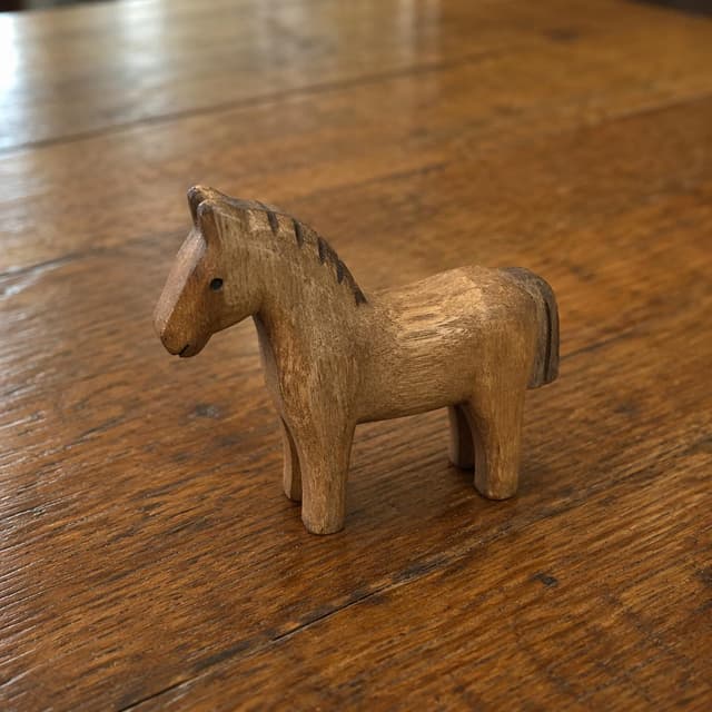 the same small carved wooden horse toy, now resting on a wooden table
Chat attachment instruction: Generate exactly one in-world chat attachment, not a collage, split-screen, comic panel, flashback, or explanatory scene. If the prompt is a screenshot, phone screen, document, note, card, map, receipt, label, object photo, or photo someone took, frame that artifact directly. A name appearing in visible text or in 'photo taken by X' is not an instruction to draw that person. Do not show recurring story participants as visible people unless the prompt itself explicitly says they are visible. Keep unrequested people, faces, and bodies out of the image.