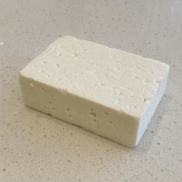 a block of white cheese on a plain kitchen counter
Chat attachment instruction: Generate exactly one in-world chat attachment, not a collage, split-screen, comic panel, flashback, or explanatory scene. If the prompt is a screenshot, phone screen, document, note, card, map, receipt, label, object photo, or photo someone took, frame that artifact directly. A name appearing in visible text or in 'photo taken by X' is not an instruction to draw that person. Do not show recurring story participants as visible people unless the prompt itself explicitly says they are visible. Keep unrequested people, faces, and bodies out of the image.