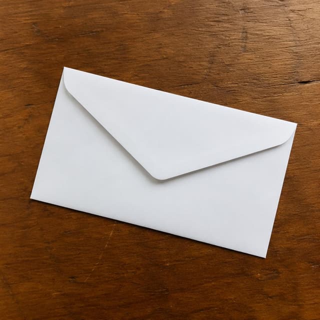 a plain white envelope on a wooden table
Chat attachment instruction: Generate exactly one in-world chat attachment, not a collage, split-screen, comic panel, flashback, or explanatory scene. If the prompt is a screenshot, phone screen, document, note, card, map, receipt, label, object photo, or photo someone took, frame that artifact directly. A name appearing in visible text or in 'photo taken by X' is not an instruction to draw that person. Do not show recurring story participants as visible people unless the prompt itself explicitly says they are visible. Keep unrequested people, faces, and bodies out of the image.