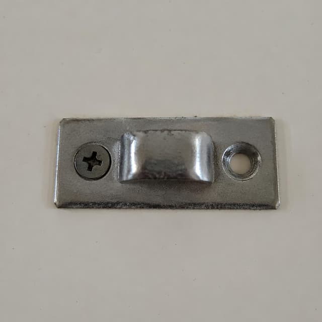 a small metal door bracket with one screw missing on a plain surface
Chat attachment instruction: Generate exactly one in-world chat attachment, not a collage, split-screen, comic panel, flashback, or explanatory scene. If the prompt is a screenshot, phone screen, document, note, card, map, receipt, label, object photo, or photo someone took, frame that artifact directly. A name appearing in visible text or in 'photo taken by X' is not an instruction to draw that person. Do not show recurring story participants as visible people unless the prompt itself explicitly says they are visible. Keep unrequested people, faces, and bodies out of the image.