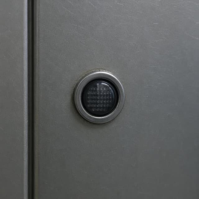 a small round indicator light on a metal door panel, unlit
Chat attachment instruction: Generate exactly one in-world chat attachment, not a collage, split-screen, comic panel, flashback, or explanatory scene. If the prompt is a screenshot, phone screen, document, note, card, map, receipt, label, object photo, or photo someone took, frame that artifact directly. A name appearing in visible text or in 'photo taken by X' is not an instruction to draw that person. Do not show recurring story participants as visible people unless the prompt itself explicitly says they are visible. Keep unrequested people, faces, and bodies out of the image.