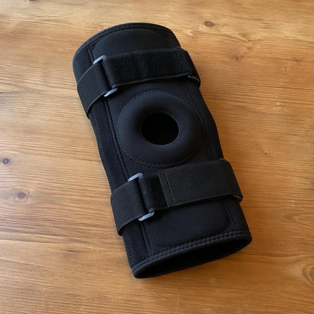 a black knee brace lying on a plain wooden table
Chat attachment instruction: Generate exactly one in-world chat attachment, not a collage, split-screen, comic panel, flashback, or explanatory scene. If the prompt is a screenshot, phone screen, document, note, card, map, receipt, label, object photo, or photo someone took, frame that artifact directly. A name appearing in visible text or in 'photo taken by X' is not an instruction to draw that person. Do not show recurring story participants as visible people unless the prompt itself explicitly says they are visible. Keep unrequested people, faces, and bodies out of the image.