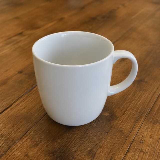 a plain white coffee cup on a wooden table
Chat attachment instruction: Generate exactly one in-world chat attachment, not a collage, split-screen, comic panel, flashback, or explanatory scene. If the prompt is a screenshot, phone screen, document, note, card, map, receipt, label, object photo, or photo someone took, frame that artifact directly. A name appearing in visible text or in 'photo taken by X' is not an instruction to draw that person. Do not show recurring story participants as visible people unless the prompt itself explicitly says they are visible. Keep unrequested people, faces, and bodies out of the image.