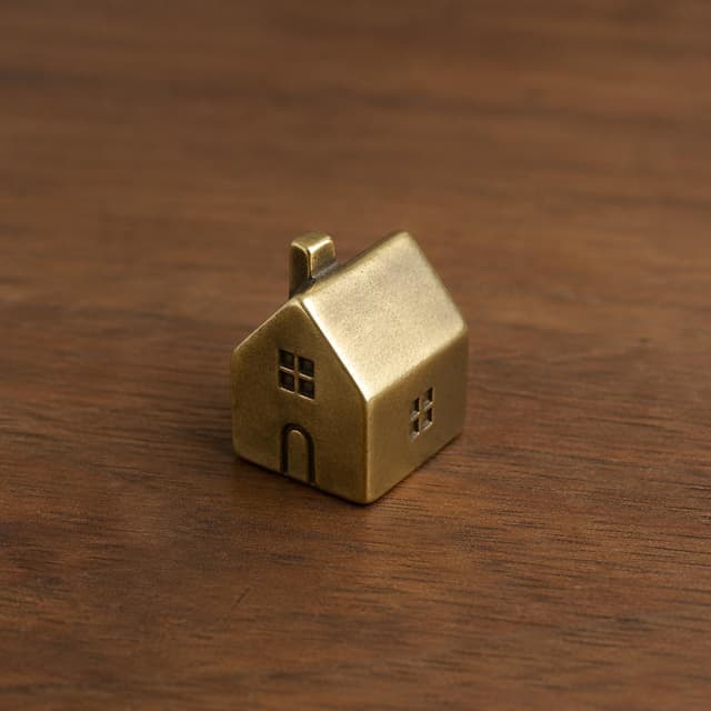 A small brass paperweight shaped like a tiny house, sitting alone on a plain wooden surface
Chat attachment instruction: Generate exactly one in-world chat attachment, not a collage, split-screen, comic panel, flashback, or explanatory scene. If the prompt is a screenshot, phone screen, document, note, card, map, receipt, label, object photo, or photo someone took, frame that artifact directly. A name appearing in visible text or in 'photo taken by X' is not an instruction to draw that person. Do not show recurring story participants as visible people unless the prompt itself explicitly says they are visible. Keep unrequested people, faces, and bodies out of the image.