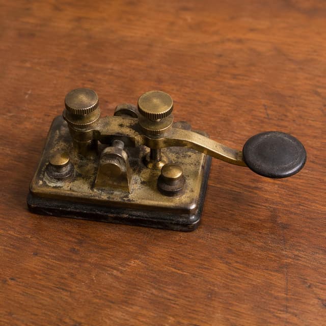 a small tarnished brass telegraph key resting on a plain wooden surface
Chat attachment instruction: Generate exactly one in-world chat attachment, not a collage, split-screen, comic panel, flashback, or explanatory scene. If the prompt is a screenshot, phone screen, document, note, card, map, receipt, label, object photo, or photo someone took, frame that artifact directly. A name appearing in visible text or in 'photo taken by X' is not an instruction to draw that person. Do not show recurring story participants as visible people unless the prompt itself explicitly says they are visible. Keep unrequested people, faces, and bodies out of the image.