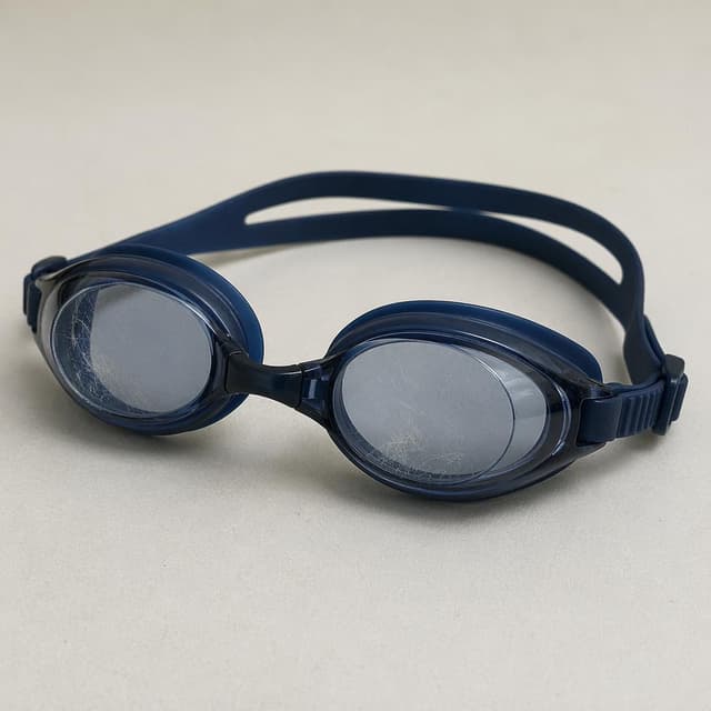 a pair of swimming goggles with a slightly scratched lens on a plain surface
Chat attachment instruction: Generate exactly one in-world chat attachment, not a collage, split-screen, comic panel, flashback, or explanatory scene. If the prompt is a screenshot, phone screen, document, note, card, map, receipt, label, object photo, or photo someone took, frame that artifact directly. A name appearing in visible text or in 'photo taken by X' is not an instruction to draw that person. Do not show recurring story participants as visible people unless the prompt itself explicitly says they are visible. Keep unrequested people, faces, and bodies out of the image.