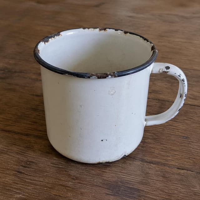 A worn white enamel mug with a chipped rim on a plain wooden table
Chat attachment instruction: Generate exactly one in-world chat attachment, not a collage, split-screen, comic panel, flashback, or explanatory scene. If the prompt is a screenshot, phone screen, document, note, card, map, receipt, label, object photo, or photo someone took, frame that artifact directly. A name appearing in visible text or in 'photo taken by X' is not an instruction to draw that person. Do not show recurring story participants as visible people unless the prompt itself explicitly says they are visible. Keep unrequested people, faces, and bodies out of the image.
