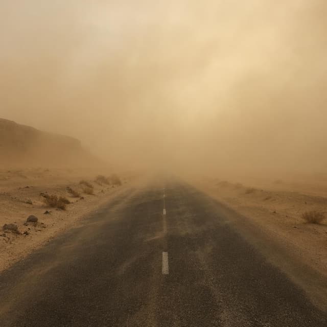 A desolate desert road disappearing into a thick haze of blowing dust, no people, no text
Chat attachment instruction: Generate exactly one in-world chat attachment, not a collage, split-screen, comic panel, flashback, or explanatory scene. If the prompt is a screenshot, phone screen, document, note, card, map, receipt, label, object photo, or photo someone took, frame that artifact directly. A name appearing in visible text or in 'photo taken by X' is not an instruction to draw that person. Do not show recurring story participants as visible people unless the prompt itself explicitly says they are visible. Keep unrequested people, faces, and bodies out of the image.
