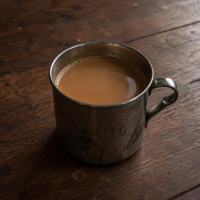 A simple worn metal cup filled with warm milky tea, sitting alone on a wooden table
Chat attachment instruction: Generate exactly one in-world chat attachment, not a collage, split-screen, comic panel, flashback, or explanatory scene. If the prompt is a screenshot, phone screen, document, note, card, map, receipt, label, object photo, or photo someone took, frame that artifact directly. A name appearing in visible text or in 'photo taken by X' is not an instruction to draw that person. Do not show recurring story participants as visible people unless the prompt itself explicitly says they are visible. Keep unrequested people, faces, and bodies out of the image.