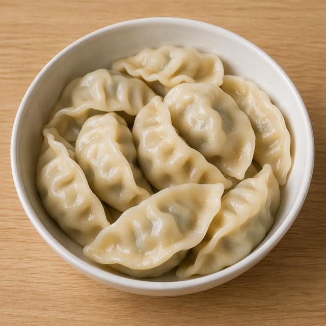 A round bowl of dumplings on a plain table
Chat attachment instruction: Generate exactly one in-world chat attachment, not a collage, split-screen, comic panel, flashback, or explanatory scene. If the prompt is a screenshot, phone screen, document, note, card, map, receipt, label, object photo, or photo someone took, frame that artifact directly. A name appearing in visible text or in 'photo taken by X' is not an instruction to draw that person. Do not show recurring story participants as visible people unless the prompt itself explicitly says they are visible. Keep unrequested people, faces, and bodies out of the image.
