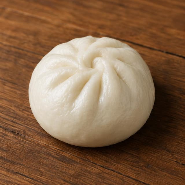 A single steamed bun on a wooden table
Chat attachment instruction: Generate exactly one in-world chat attachment, not a collage, split-screen, comic panel, flashback, or explanatory scene. If the prompt is a screenshot, phone screen, document, note, card, map, receipt, label, object photo, or photo someone took, frame that artifact directly. A name appearing in visible text or in 'photo taken by X' is not an instruction to draw that person. Do not show recurring story participants as visible people unless the prompt itself explicitly says they are visible. Keep unrequested people, faces, and bodies out of the image.