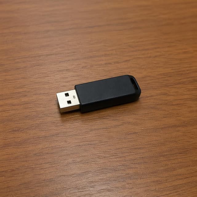 a small black USB flash drive resting on a plain wooden desk
Chat attachment instruction: Generate exactly one in-world chat attachment, not a collage, split-screen, comic panel, flashback, or explanatory scene. If the prompt is a screenshot, phone screen, document, note, card, map, receipt, label, object photo, or photo someone took, frame that artifact directly. A name appearing in visible text or in 'photo taken by X' is not an instruction to draw that person. Do not show recurring story participants as visible people unless the prompt itself explicitly says they are visible. Keep unrequested people, faces, and bodies out of the image.