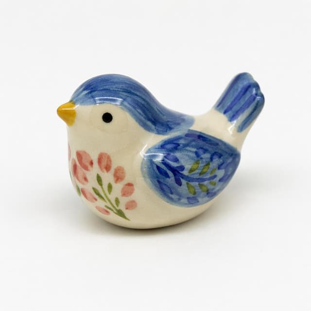 a small hand-painted ceramic bird figurine on a plain white surface
Chat attachment instruction: Generate exactly one in-world chat attachment, not a collage, split-screen, comic panel, flashback, or explanatory scene. If the prompt is a screenshot, phone screen, document, note, card, map, receipt, label, object photo, or photo someone took, frame that artifact directly. A name appearing in visible text or in 'photo taken by X' is not an instruction to draw that person. Do not show recurring story participants as visible people unless the prompt itself explicitly says they are visible. Keep unrequested people, faces, and bodies out of the image.