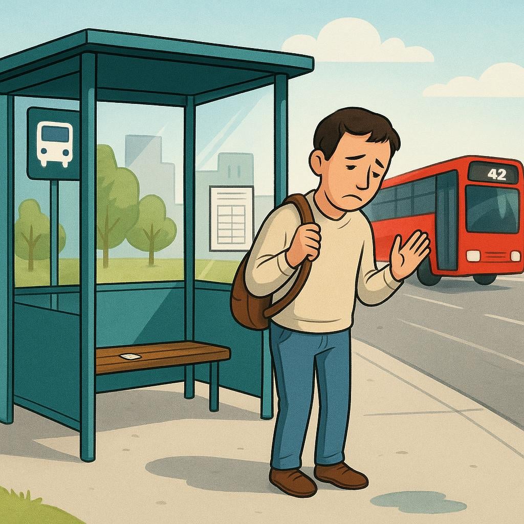 An adult standing alone at a bus stop shelter, watching the back of a large red bus driving quickly away into the distance.