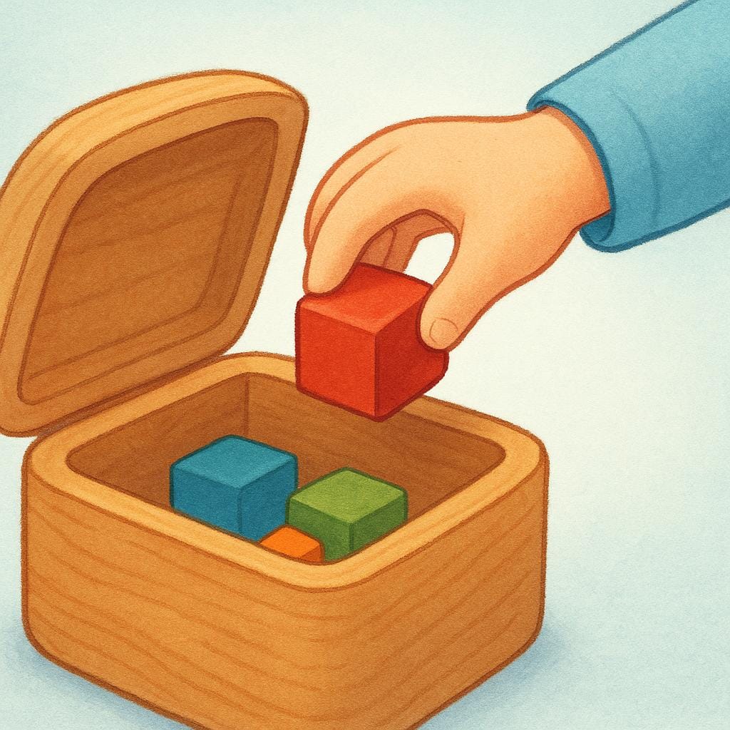 A small child putting a colorful wooden block into a large, open toy chest, illustrating the action of storing an object.