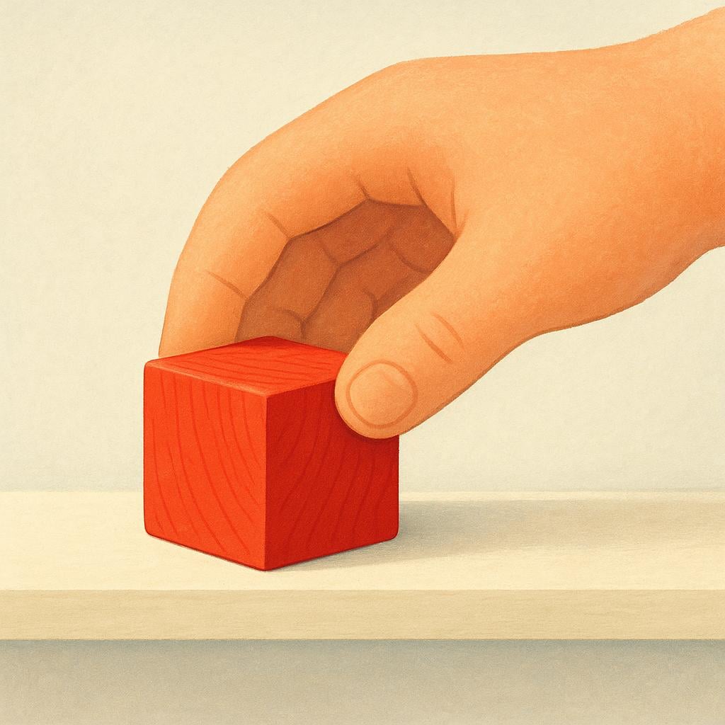 A human hand carefully placing a small, colorful red wooden block onto a smooth wooden shelf.