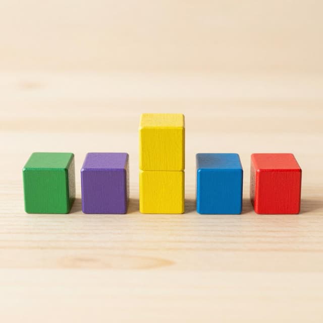 A row of colorful wooden blocks perfectly aligned in a straight horizontal line on a wooden floor.