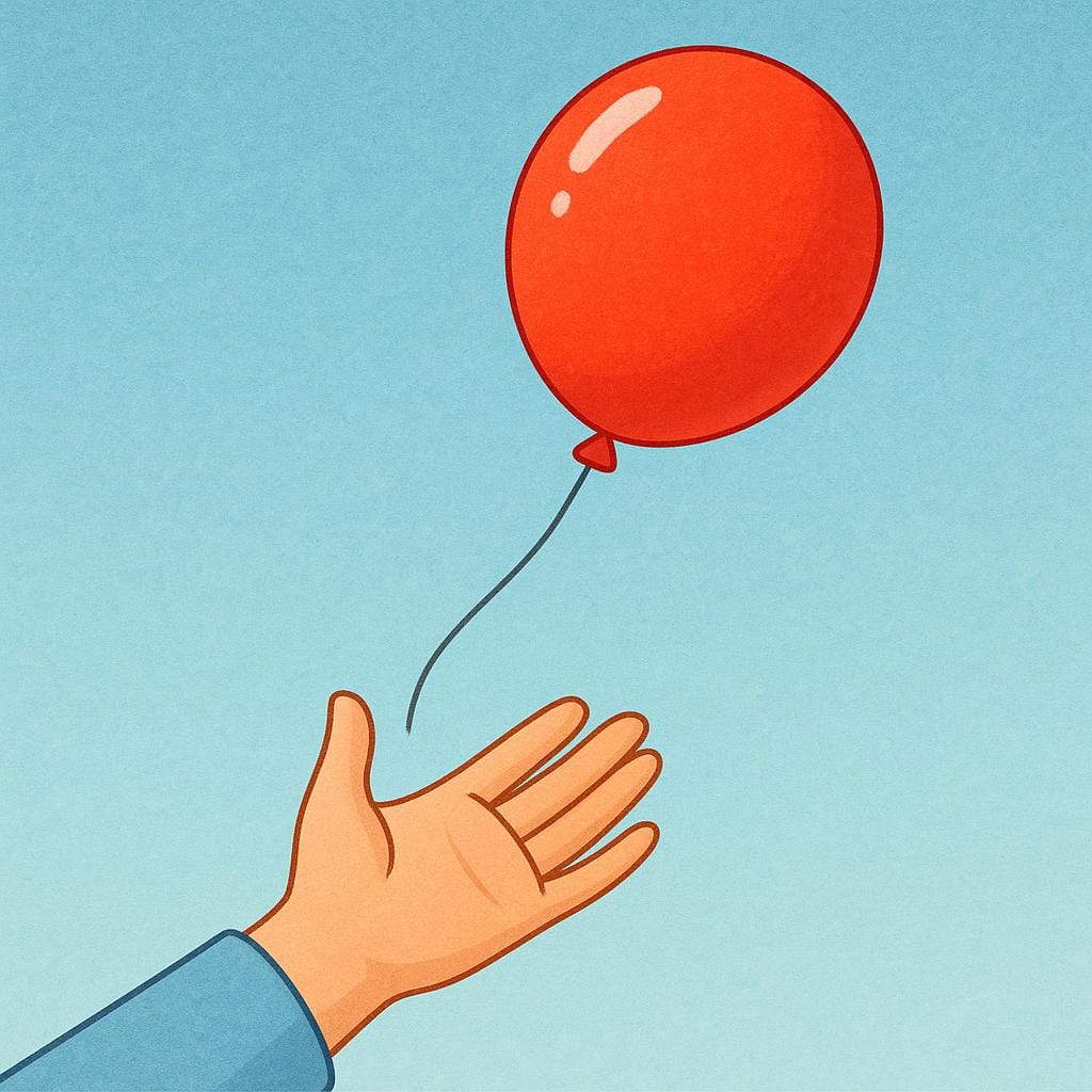 A person's hand gently releasing a brightly colored red balloon into the open air, symbolizing the act of releasing.
