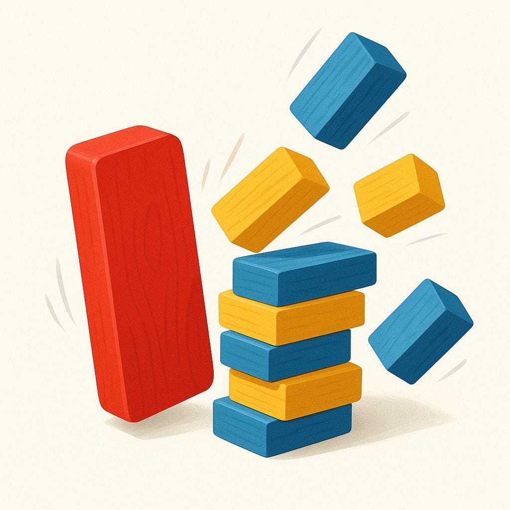 A single red domino tipping over and making contact with a stack of colorful wooden blocks, clearly showing the action that causes the blocks to scatter.