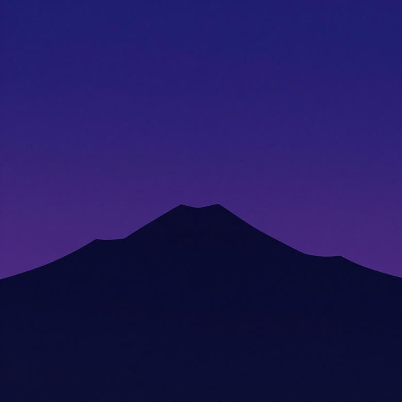 A landscape showing the sun disappearing behind a mountain range as the sky turns a deep indigo.