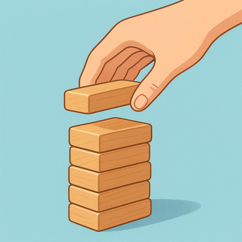 A large hand gently placing a small, colorful wooden block onto a stack of blocks.