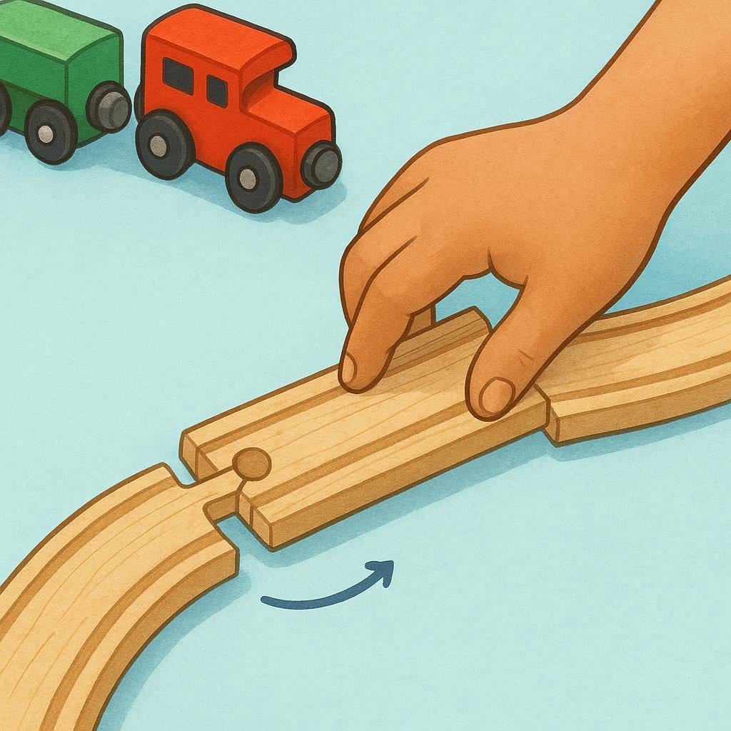 A child's hand is physically moving a section of a wooden toy train track to create a new, modified path, altering the original setup.