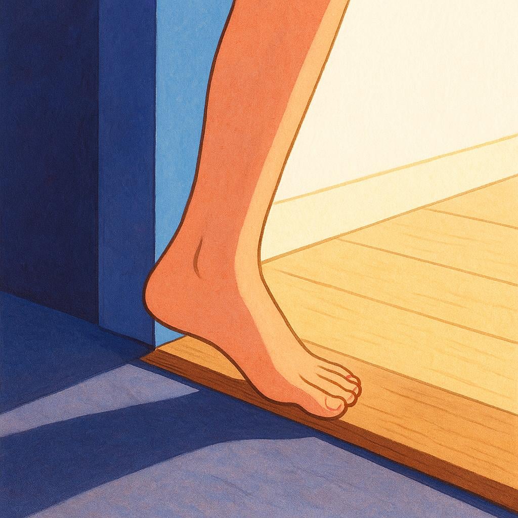 A person's foot stepping over the threshold of a doorway from a dark exterior into a brightly lit interior room.