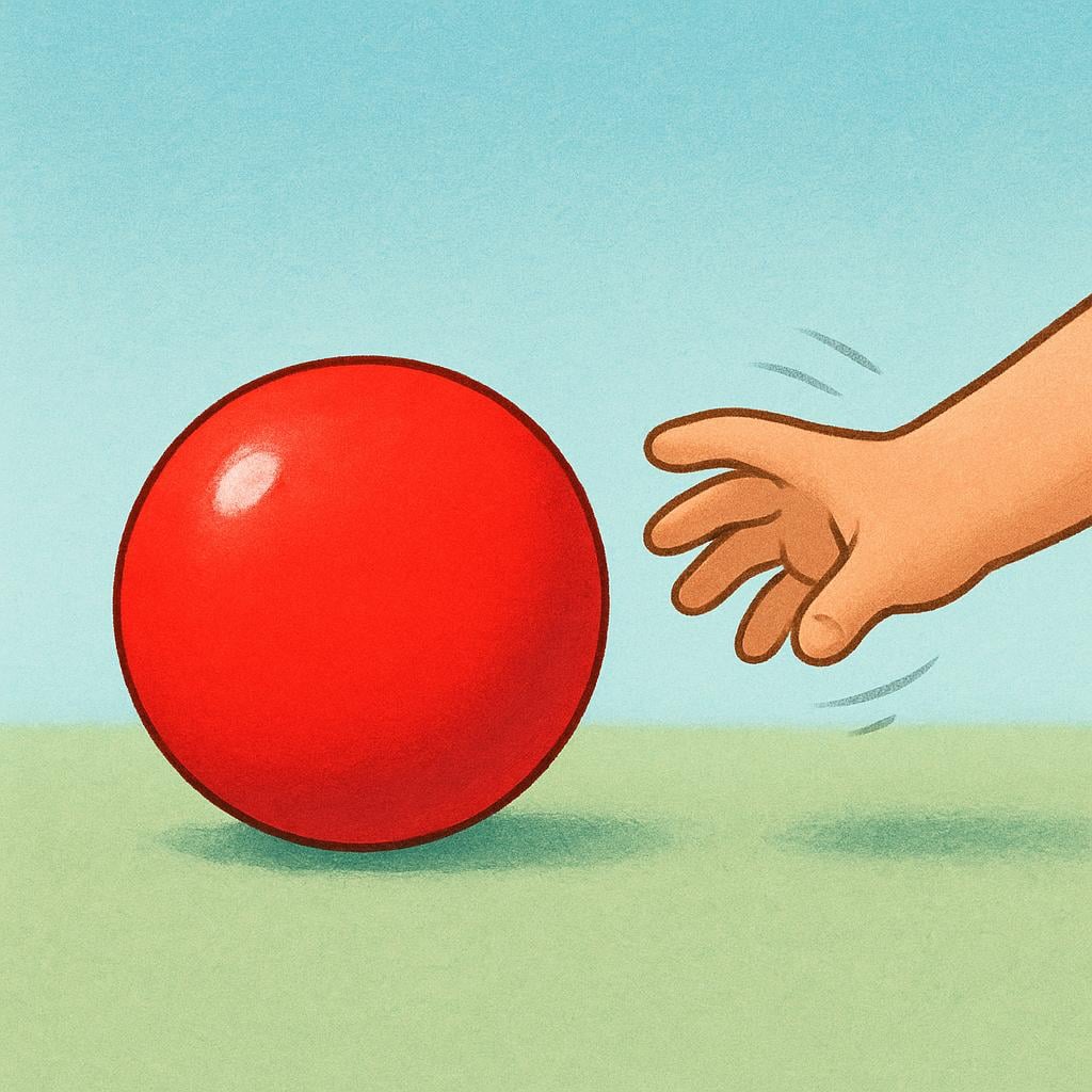 A close-up view of a small, brightly colored red ball resting on a wooden floor. A child's hand is visible above the ball, clearly retracting and pulling away from the object, signifying the action of leaving it alone.