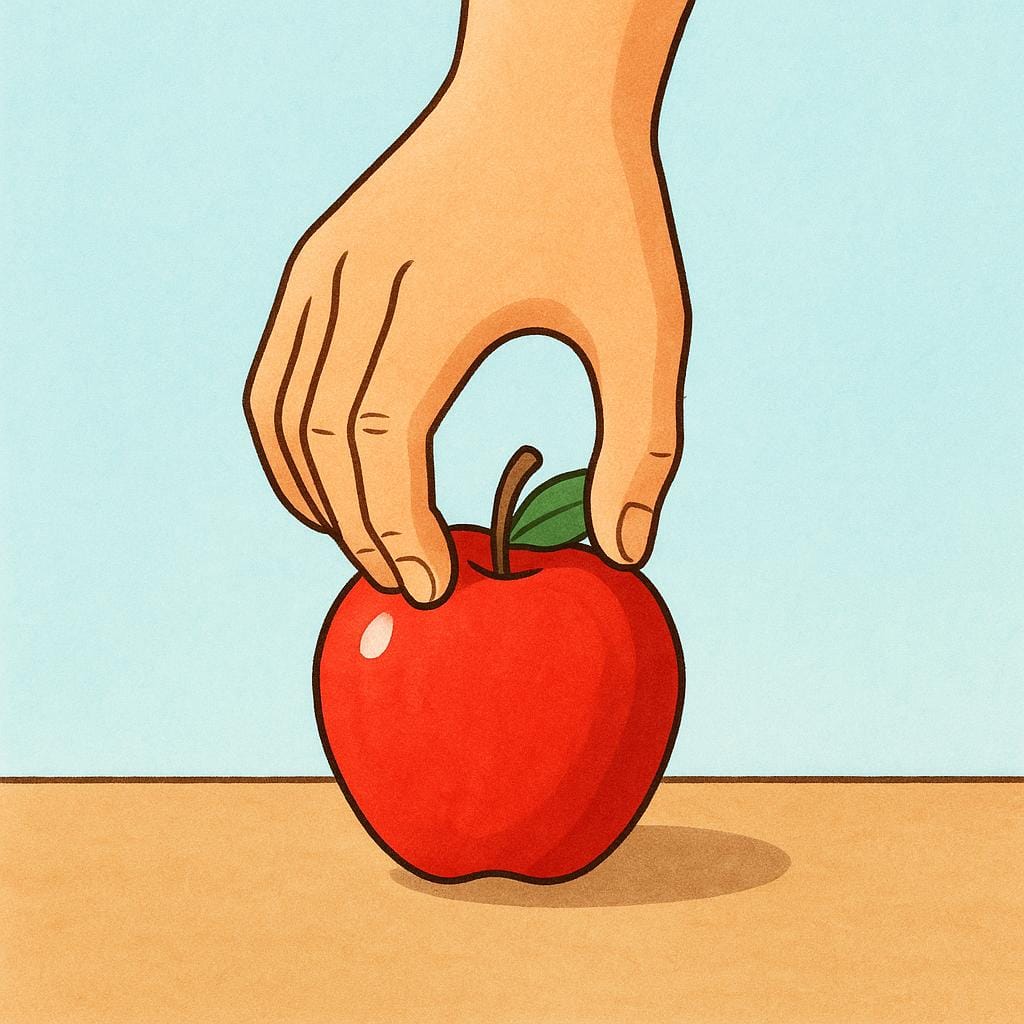 A person's hand reaching down and firmly grasping a bright red apple resting on a table.