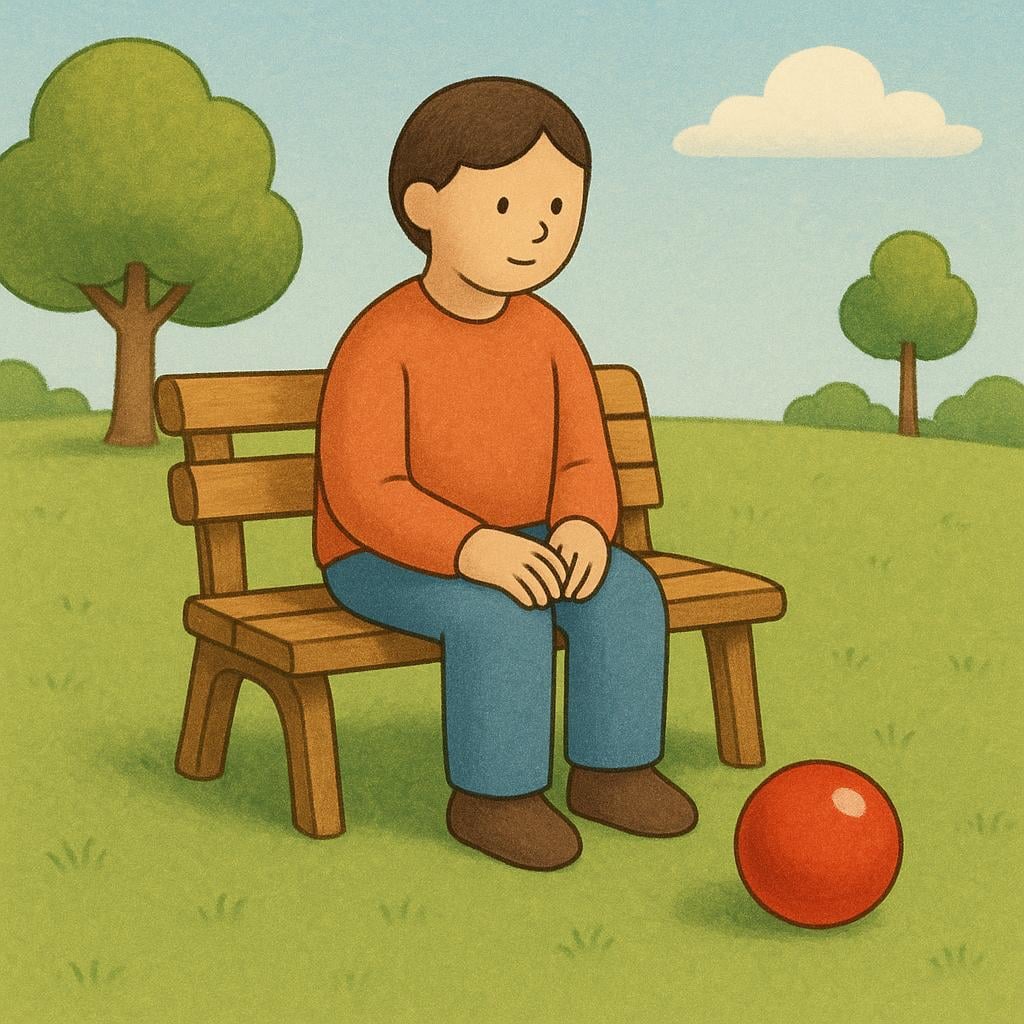 A person sitting on a park bench with a bright red ball resting on the ground close to their feet.